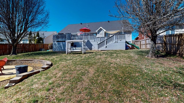 back of house featuring a yard, a wooden deck, an outdoor fire pit, and a fenced backyard