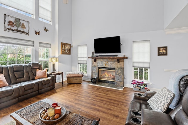 living area with a tile fireplace, a high ceiling, baseboards, and wood finished floors