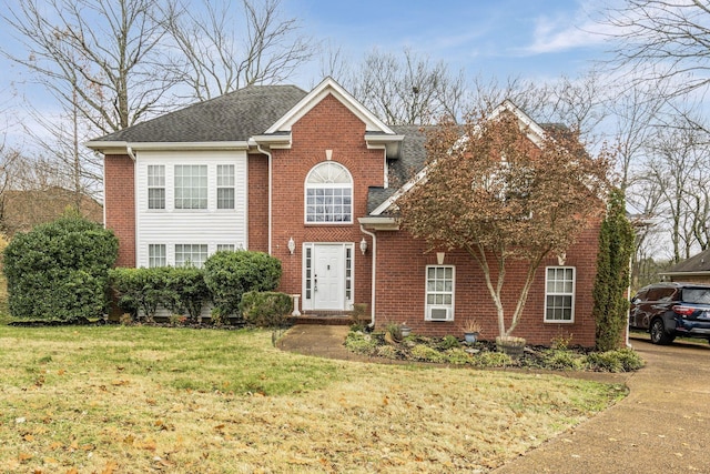 view of front of home with brick siding, a shingled roof, and a front yard