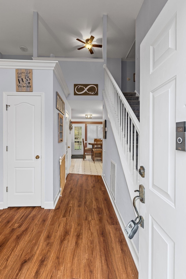 foyer entrance with visible vents, dark wood-style floors, baseboards, ceiling fan, and stairs