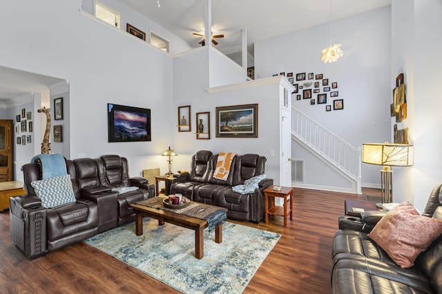 living room featuring visible vents, wood finished floors, baseboards, a towering ceiling, and stairs