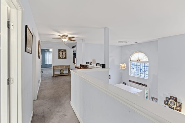 corridor featuring an upstairs landing, baseboards, and light carpet