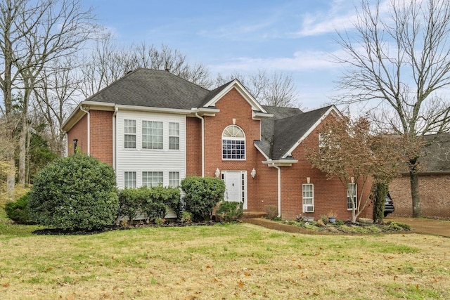 view of front facade with brick siding, a front lawn, and a shingled roof