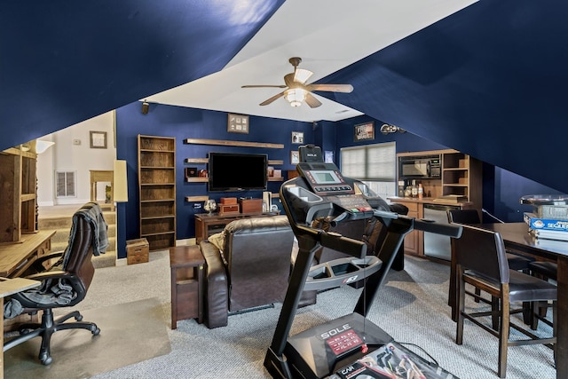 carpeted office with lofted ceiling, a ceiling fan, and visible vents