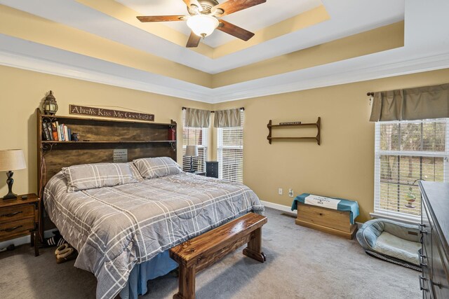 bedroom with a tray ceiling, baseboards, carpet, and a ceiling fan