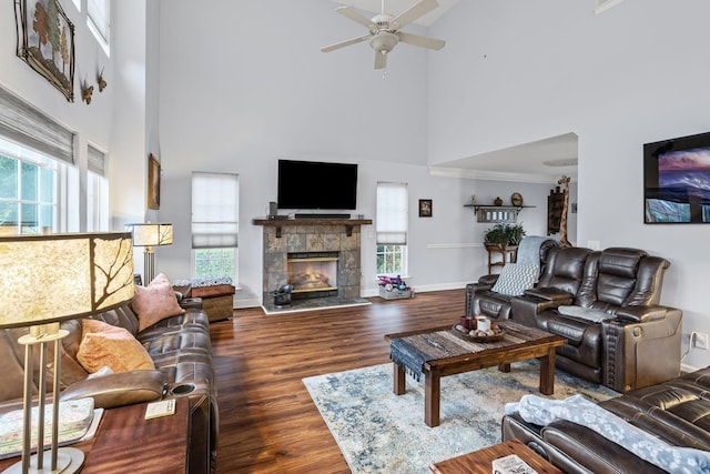 living area with a wealth of natural light, a glass covered fireplace, baseboards, and wood finished floors