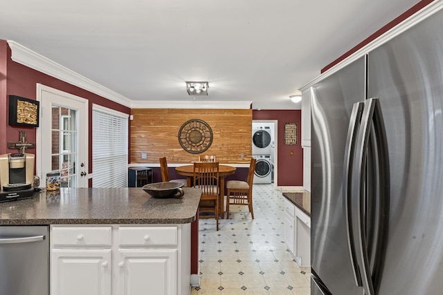 kitchen with dark countertops, light floors, stacked washer / drying machine, and freestanding refrigerator