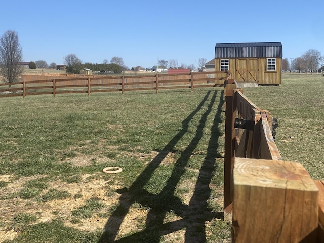 view of yard featuring a rural view, a storage unit, an outdoor structure, and fence