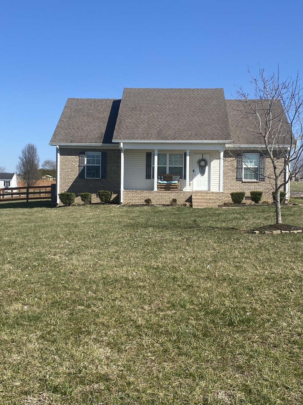 single story home with brick siding, a front lawn, and fence