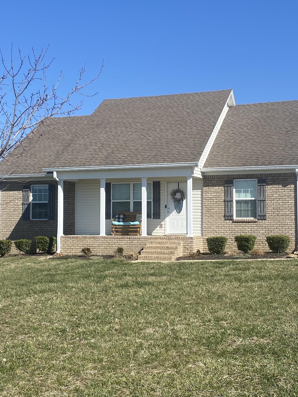 ranch-style house with brick siding, roof with shingles, and a front yard