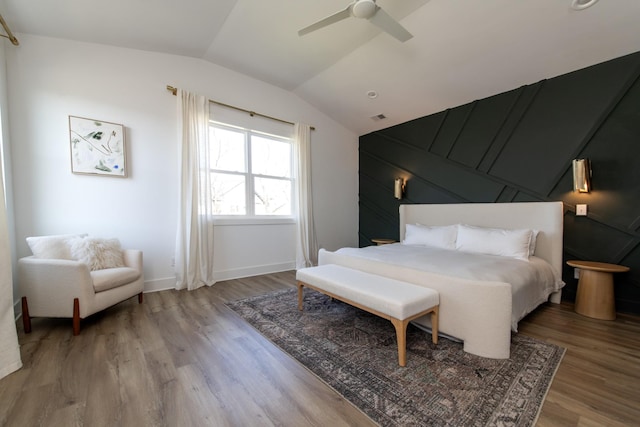 bedroom with vaulted ceiling, wood finished floors, visible vents, and ceiling fan