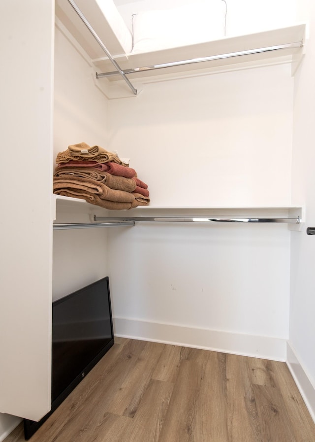 walk in closet with wood finished floors