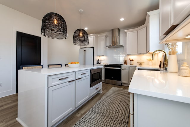 kitchen with a kitchen island, dark wood finished floors, a sink, stainless steel appliances, and wall chimney exhaust hood