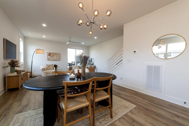 dining space with wood finished floors, visible vents, baseboards, recessed lighting, and stairs