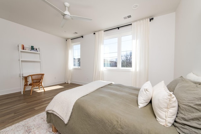 bedroom featuring visible vents, a ceiling fan, baseboards, and wood finished floors