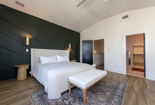 bedroom with visible vents, wood finished floors, baseboards, and vaulted ceiling