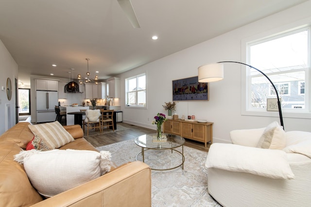 living room with recessed lighting, baseboards, light wood finished floors, and a chandelier