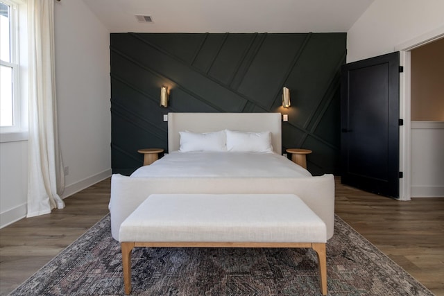 bedroom featuring visible vents, baseboards, and wood finished floors