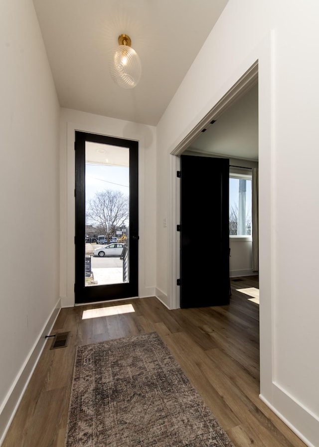 foyer entrance with visible vents, baseboards, and wood finished floors