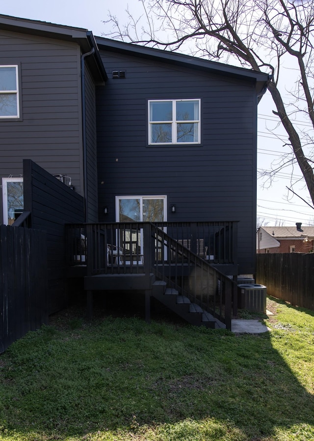 back of house featuring a deck, fence, a lawn, and central AC