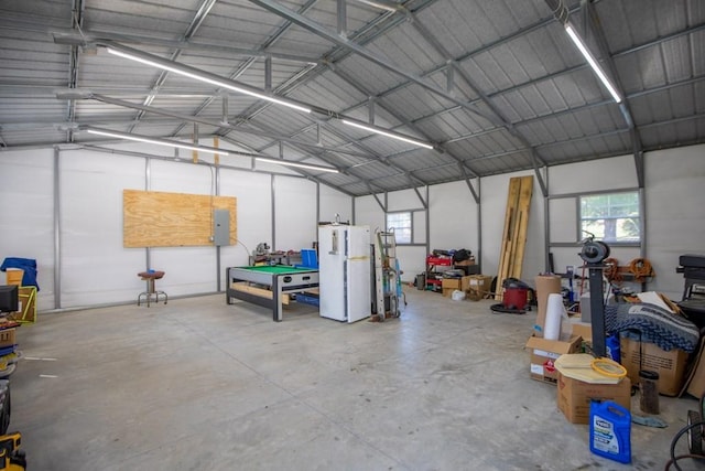 garage featuring electric panel, metal wall, and freestanding refrigerator