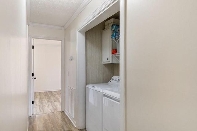 laundry area with visible vents, light wood finished floors, ornamental molding, a textured ceiling, and washing machine and dryer