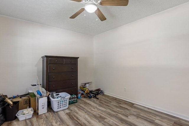 interior space featuring baseboards, a textured ceiling, wood finished floors, and a ceiling fan