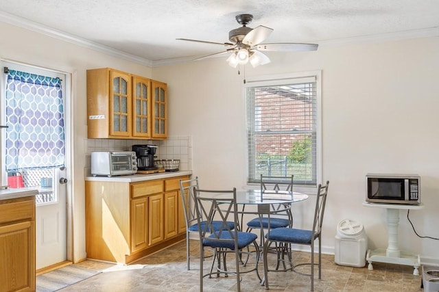 kitchen featuring a toaster, light countertops, glass insert cabinets, stainless steel microwave, and tasteful backsplash