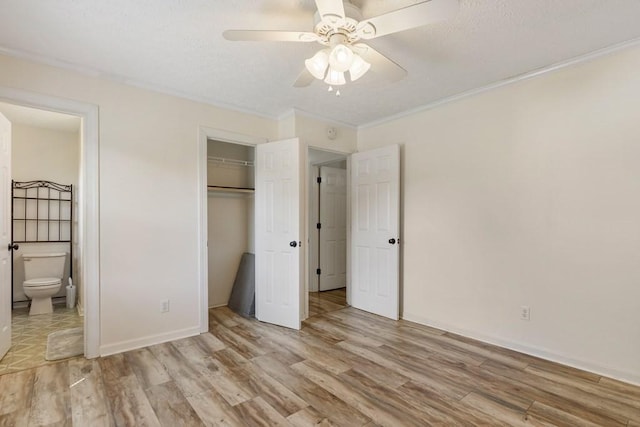 unfurnished bedroom with light wood-type flooring, a textured ceiling, ensuite bath, and crown molding