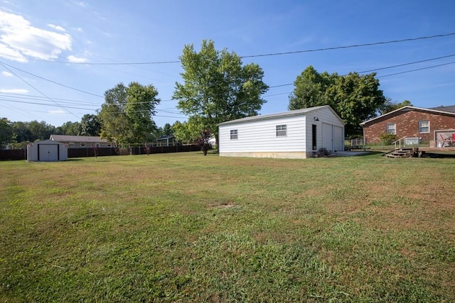 view of yard with an outdoor structure, a shed, fence, and a detached garage