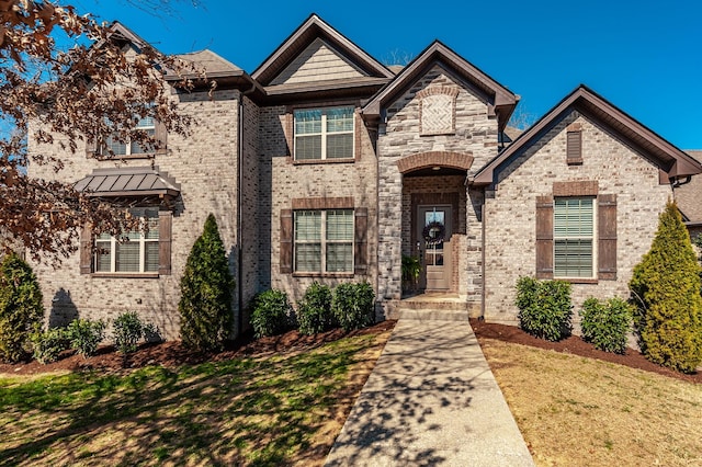 view of front of home with a front lawn, brick siding, and stone siding