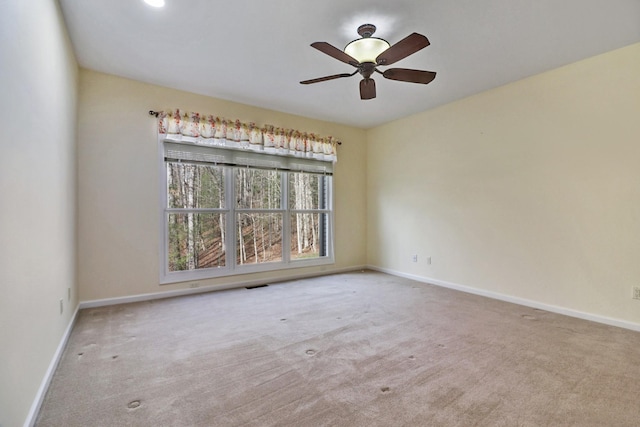 empty room featuring carpet flooring, ceiling fan, baseboards, and visible vents