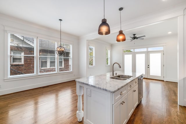 kitchen with dishwasher, decorative light fixtures, wood finished floors, and a sink