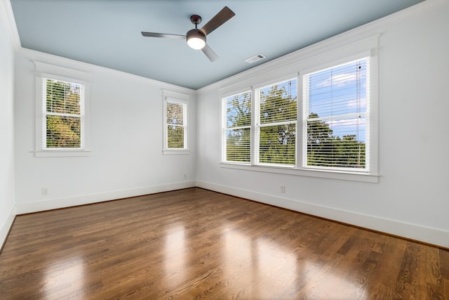 unfurnished room featuring wood finished floors, visible vents, a wealth of natural light, and baseboards