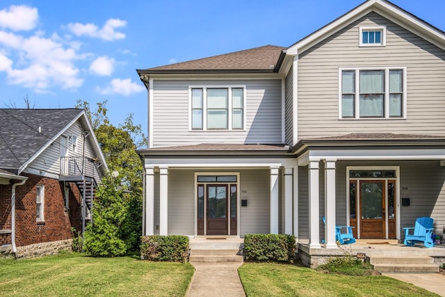 view of front of property with a front yard, covered porch, and a shingled roof