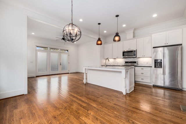 kitchen featuring backsplash, white cabinetry, appliances with stainless steel finishes, a breakfast bar area, and dark wood-style flooring