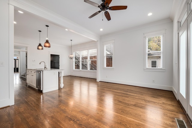 unfurnished living room with visible vents, crown molding, baseboards, and dark wood-style flooring