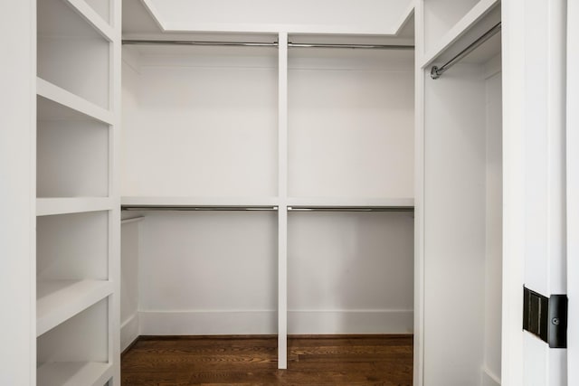 walk in closet with dark wood-style floors