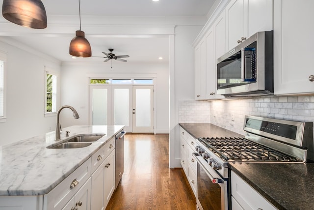 kitchen featuring a sink, backsplash, appliances with stainless steel finishes, white cabinets, and dark wood-style flooring