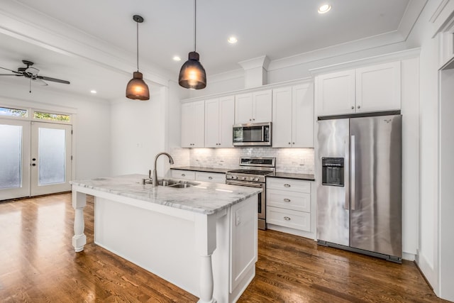 kitchen with a kitchen island with sink, a sink, decorative backsplash, appliances with stainless steel finishes, and white cabinetry