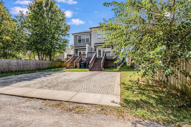 view of front of home with stairway, fence private yard, and a front lawn