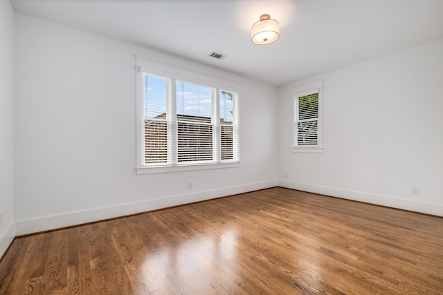 unfurnished room with visible vents, baseboards, and wood finished floors