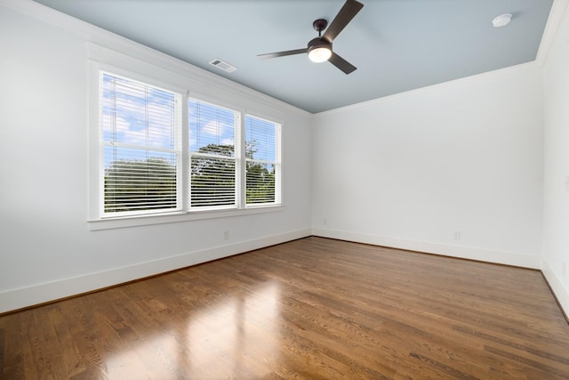 spare room featuring visible vents, wood finished floors, crown molding, baseboards, and ceiling fan