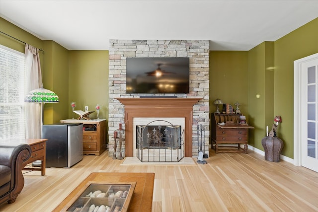 living room featuring a fireplace, baseboards, and wood finished floors