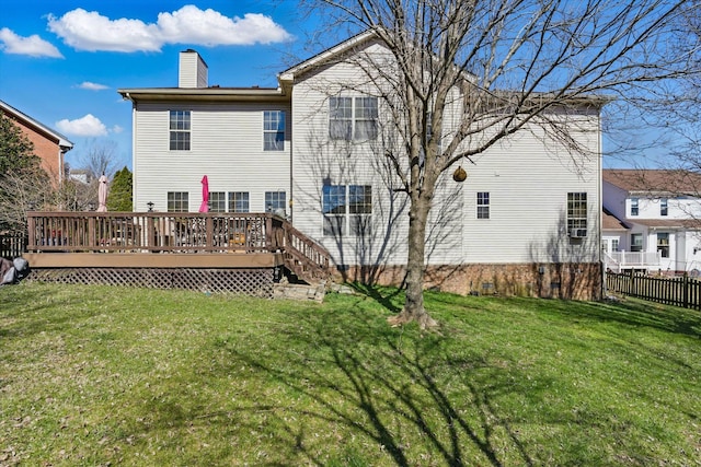 back of property featuring a wooden deck, fence, a lawn, and a chimney