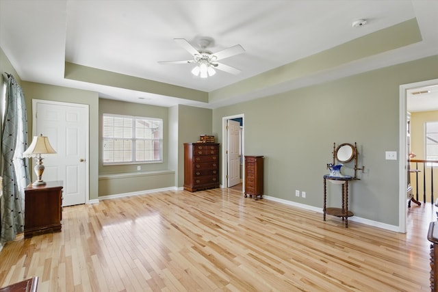 bedroom featuring baseboards, a raised ceiling, and light wood-style floors