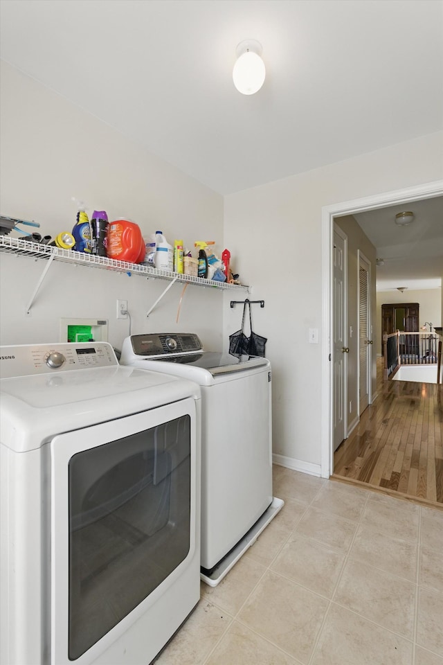 washroom featuring laundry area, light tile patterned floors, baseboards, and washing machine and clothes dryer