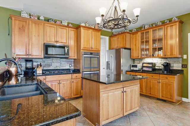 kitchen featuring a sink, dark stone countertops, backsplash, stainless steel appliances, and glass insert cabinets