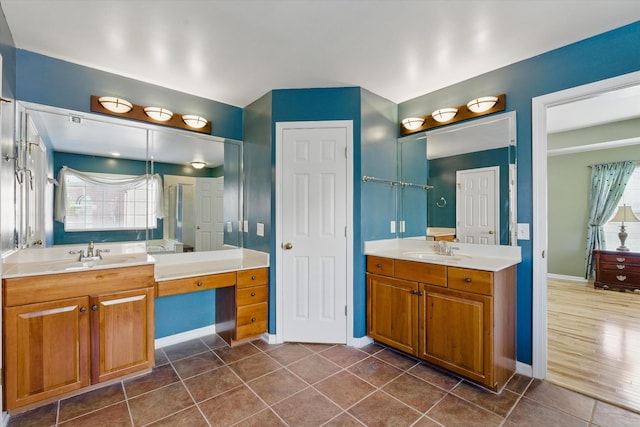 bathroom with tile patterned floors, two vanities, baseboards, and a sink