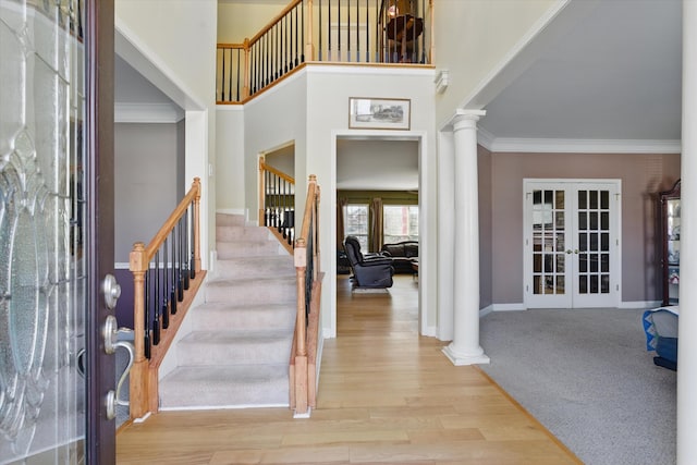 foyer entrance featuring wood finished floors, decorative columns, french doors, and ornamental molding